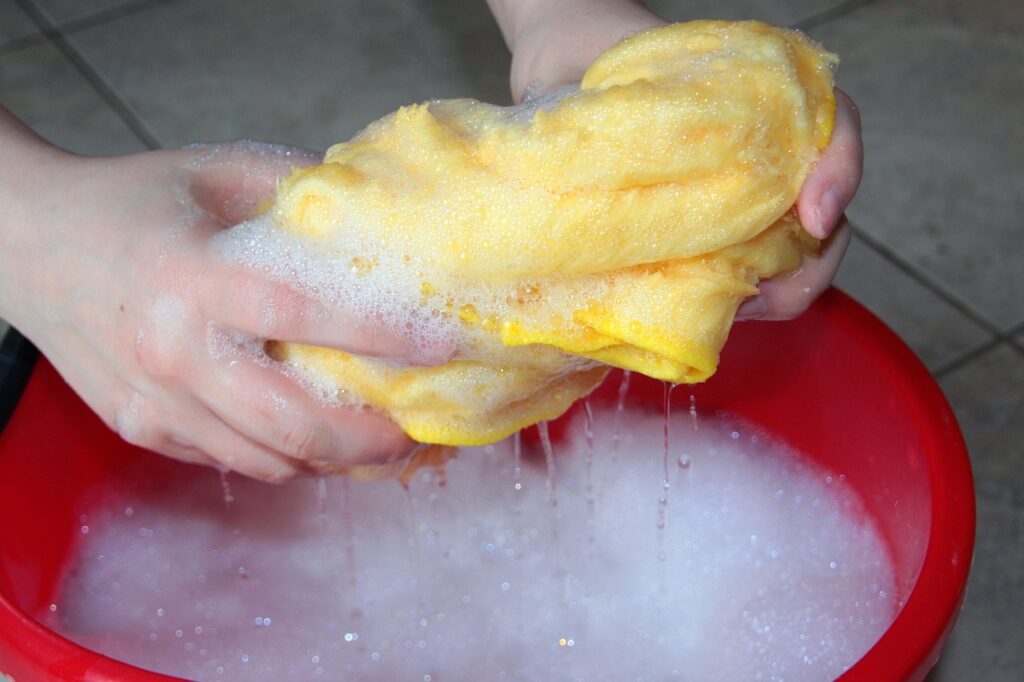Professional cleaner wringing out rag into mop bucket with soapy water during deep cleaning service in Olympia, WA
